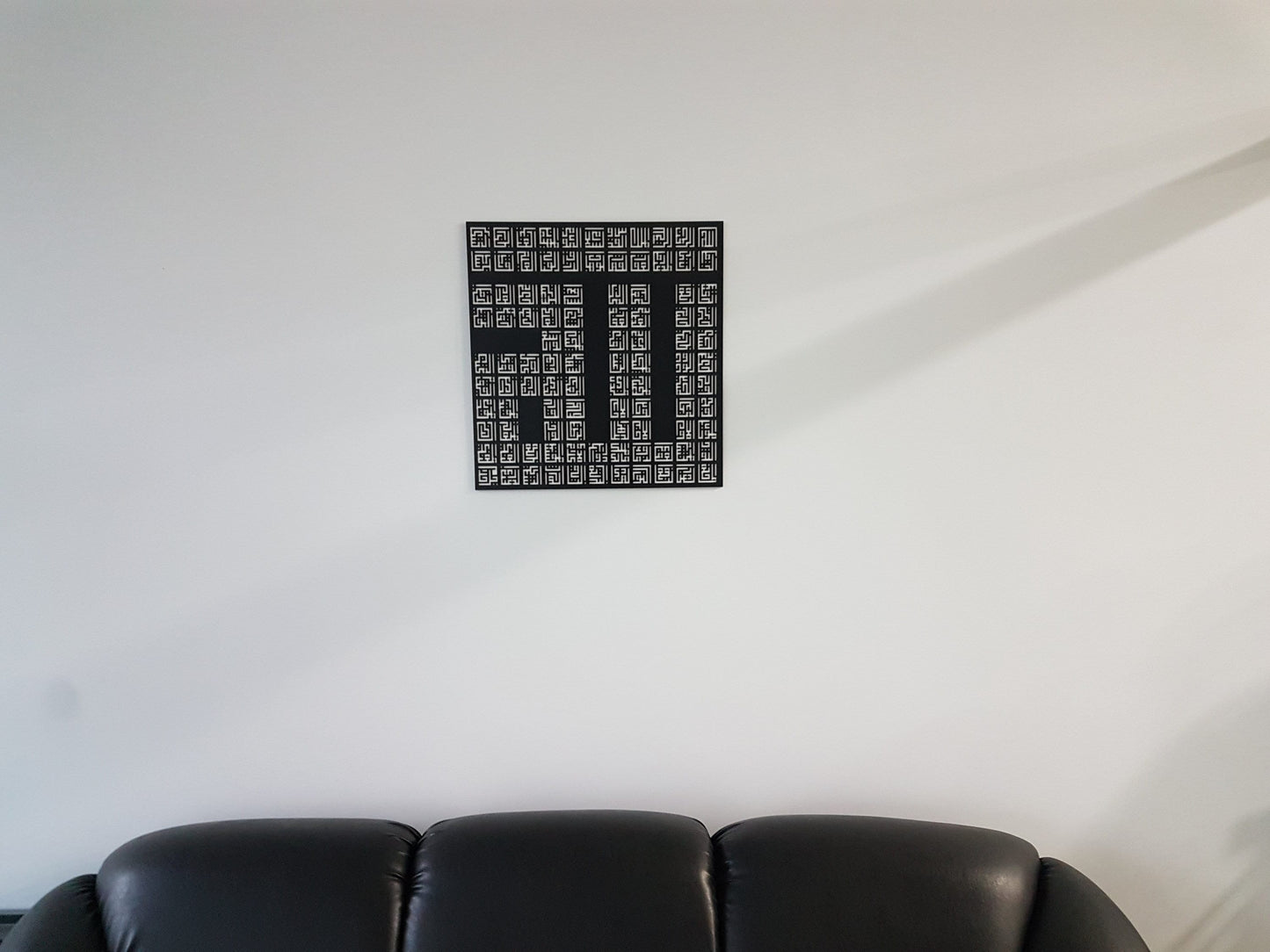 Asma-ul-Husna square wall art hung above a black leather sofa