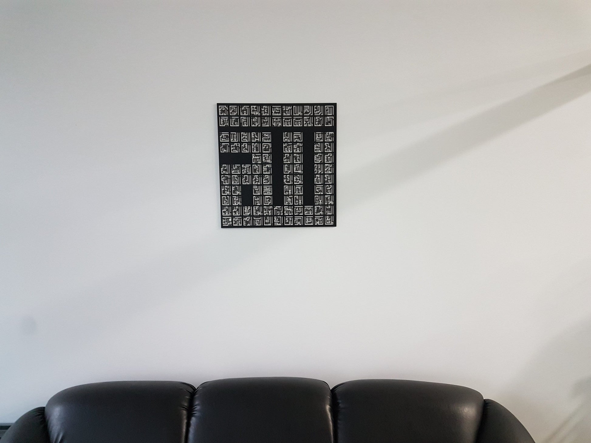 Asma-ul-Husna square wall art hung above a black leather sofa